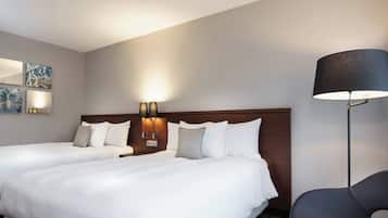 Une chambre d’hôtel avec deux lits, une tête de lit en bois, des lampes fixées au mur et un fauteuil moderne.