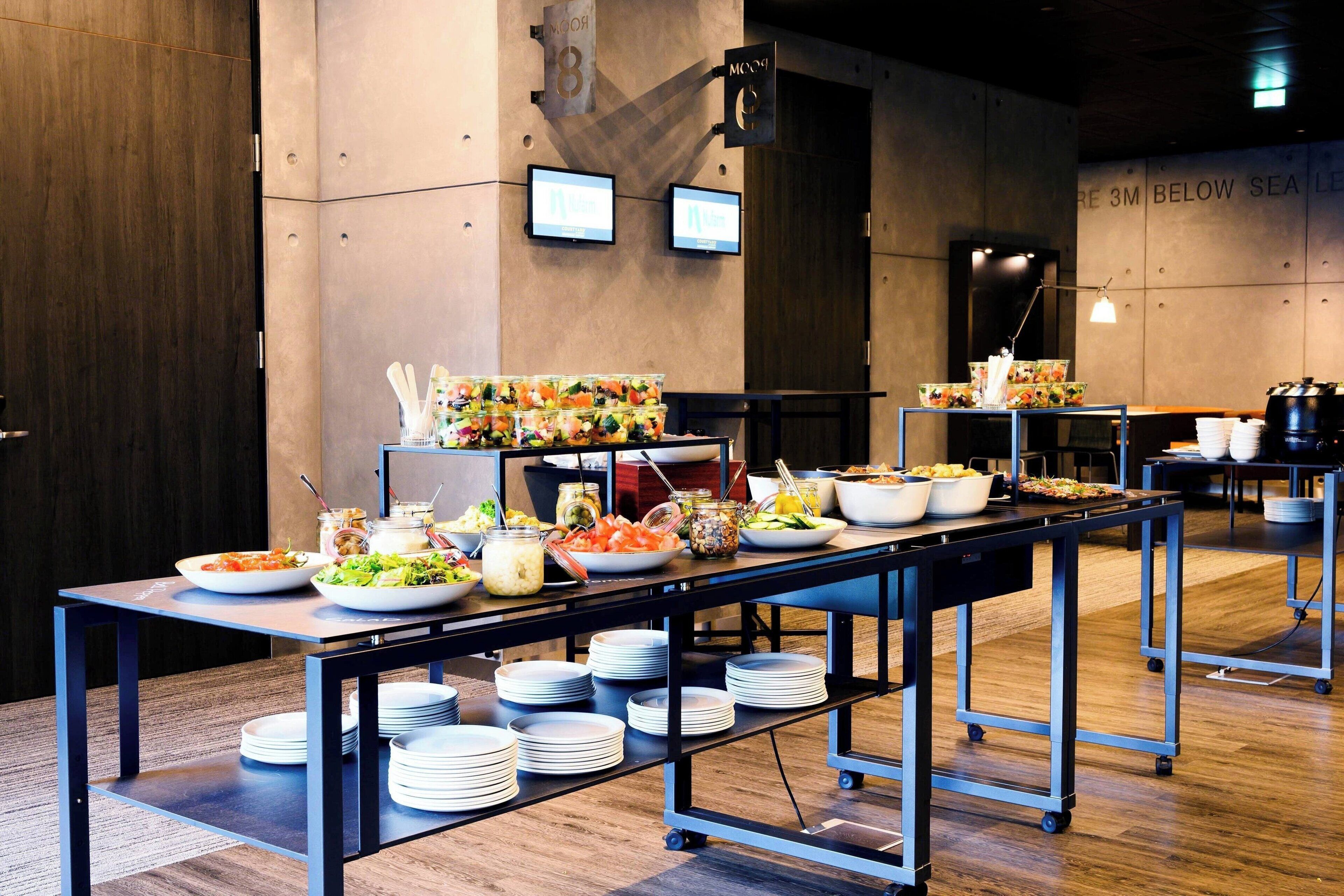 A buffet setup with various food items and bowls on tables, with a sign indicating "3M BELOW SEA LEVEL" on the wall.