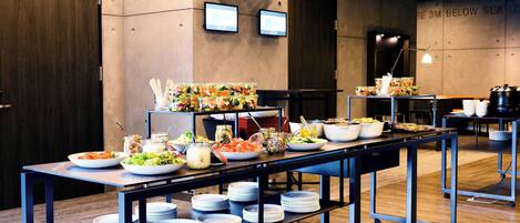 A buffet setup with various food items and bowls on tables, with a sign indicating "3M BELOW SEA LEVEL" on the wall.