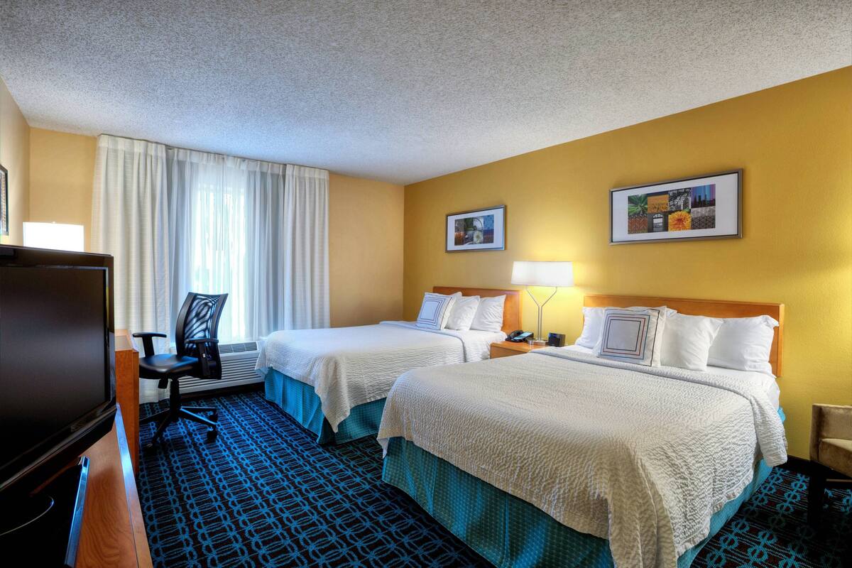 Une chambre d’hôtel avec deux lits, une télévision, un bureau et une chaise.