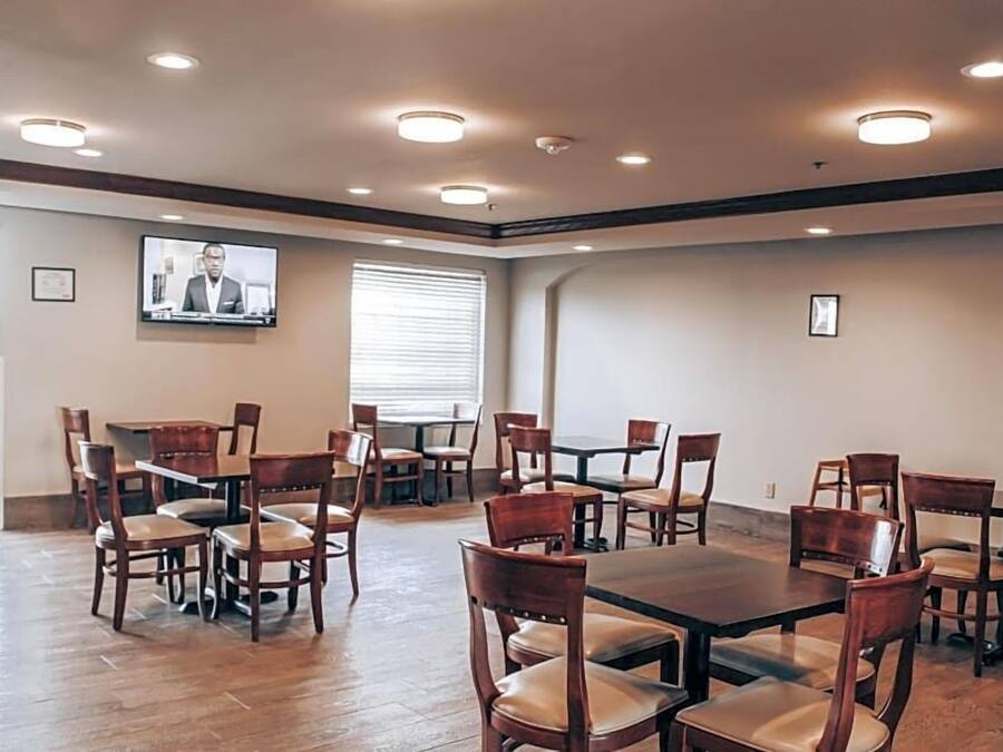 A conference room with multiple tables and chairs, a television screen, and a window with blinds.