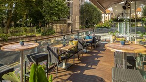 A covered outdoor seating area with wicker furniture and potted plants.