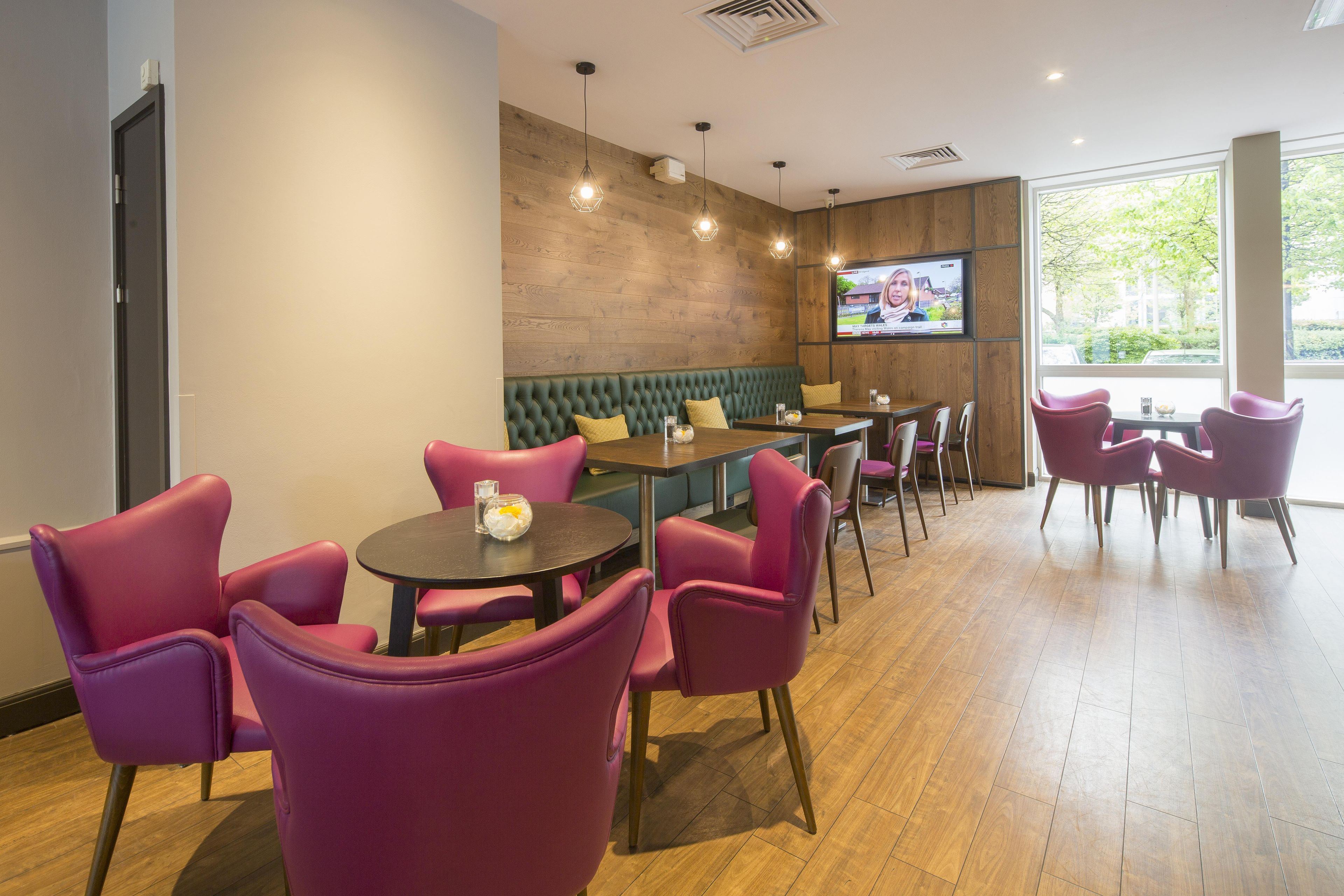 A modern lounge area with seating, a television screen, and a wooden wall.