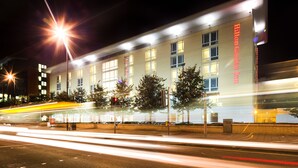 A hotel with a modern facade, multiple windows, and a prominent neon sign.