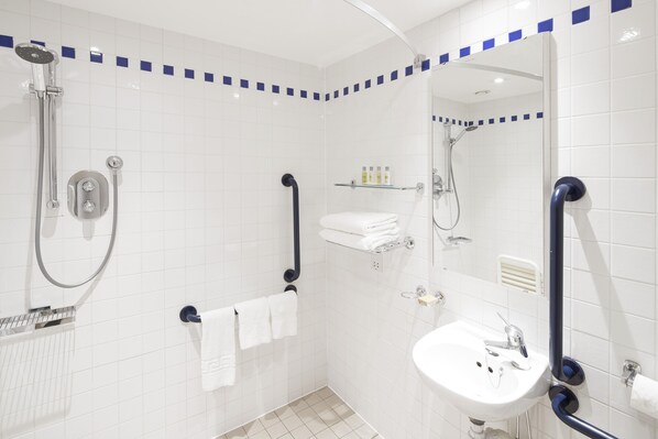Un baño moderno con ducha a nivel, lavamanos y espejo.