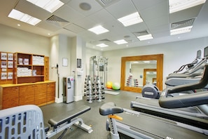 A gym with exercise equipment, a mirror, and a towel rack. - Hilton Garden Inn Bristol City Centre (Bristol)