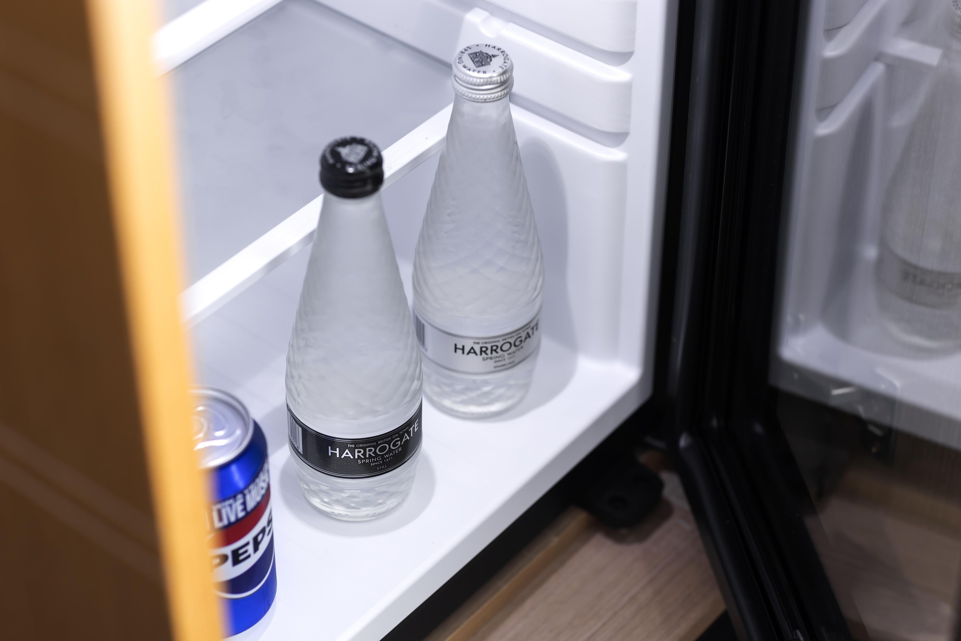 A refrigerator with two bottles labeled 'Harrogate' and a can of 'Pepsi'.