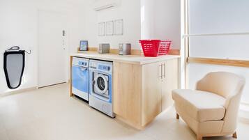 A modern laundry room with a washing machine, dryer, and a red laundry basket on the counter.