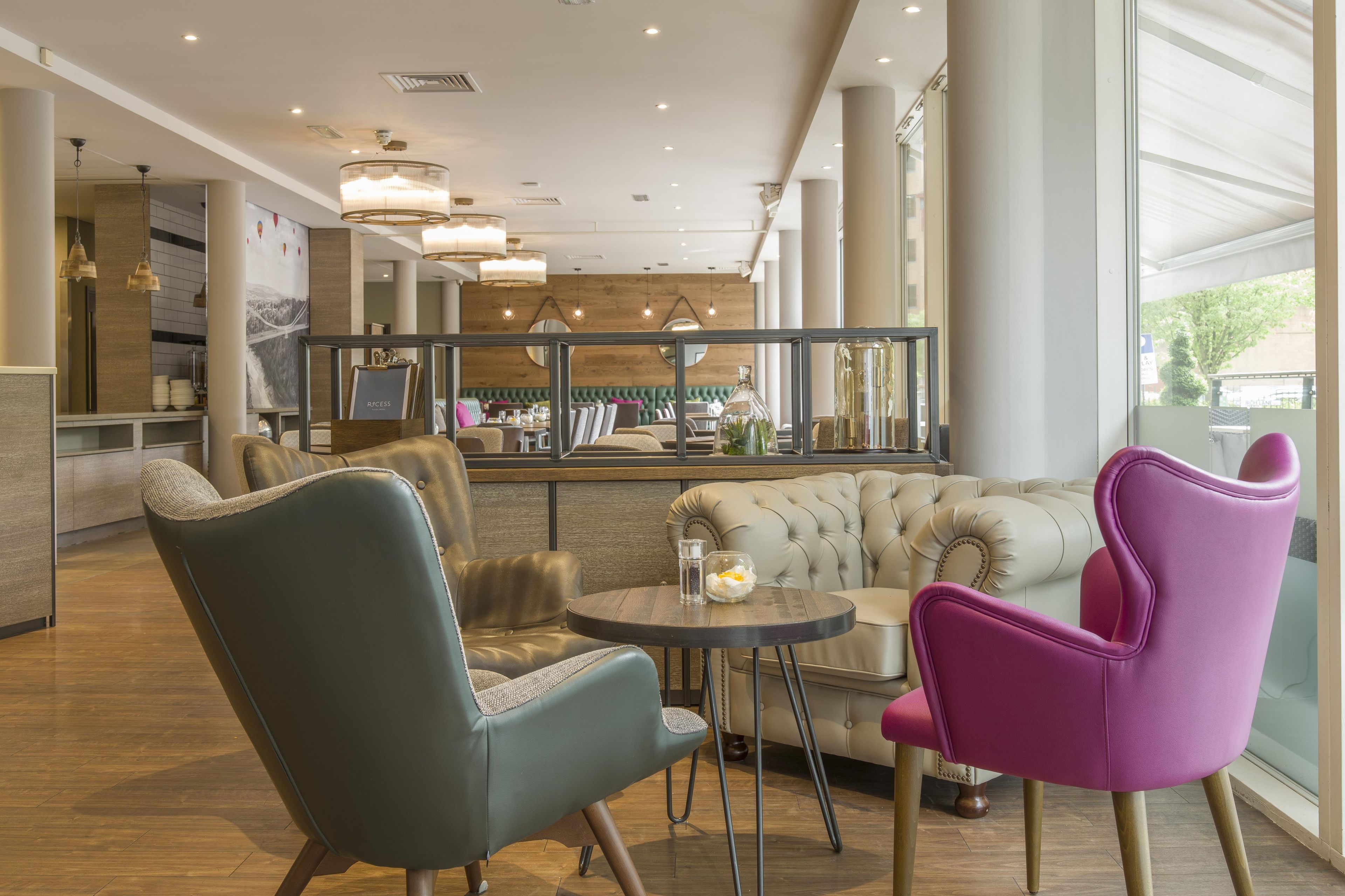 Un intérieur moderne comprenant un espace salon, un bar et une vue dégagée sur l’extérieur grâce à de grandes fenêtres.