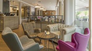 A modern lounge area with leather sofas, a round table, and a bar area in the background.