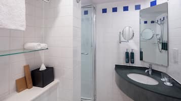 A modern bathroom with a glass-enclosed shower, a sink with a dark countertop, and a mirror above the sink.