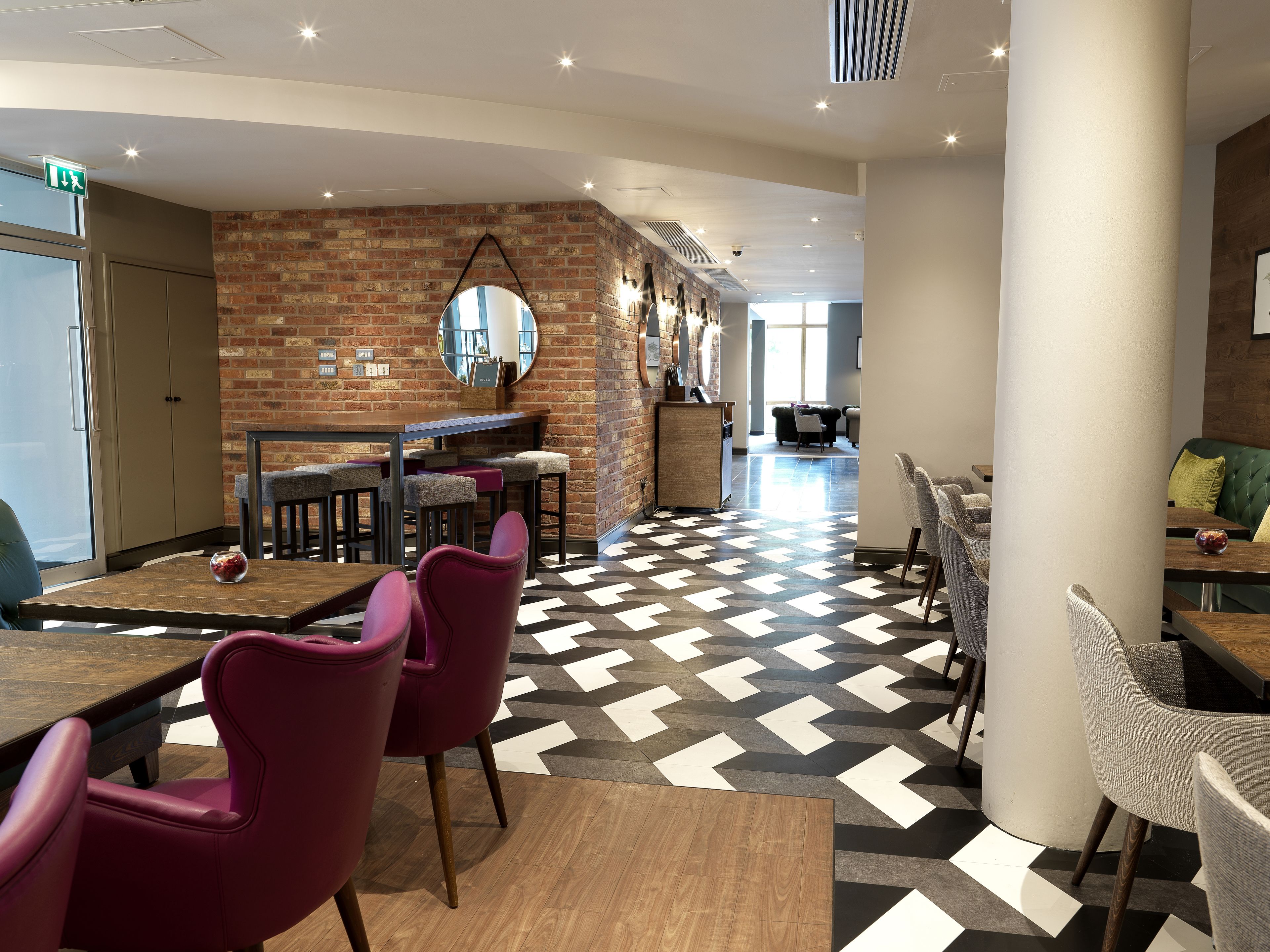 A modern interior with a brick wall, a round mirror, and a checkered floor.