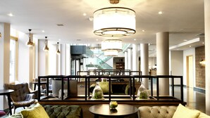 A spacious lobby with a central seating area, a staircase, and a modern chandelier. - Hilton Garden Inn Birmingham Brindley Place (Birmingham)