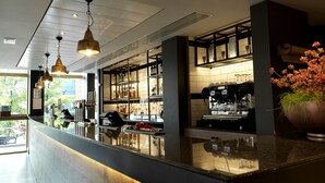 A modern bar area with a polished granite countertop, overhead pendant lighting, and a coffee machine. - Hilton Garden Inn Birmingham Brindley Place (Birmingham)