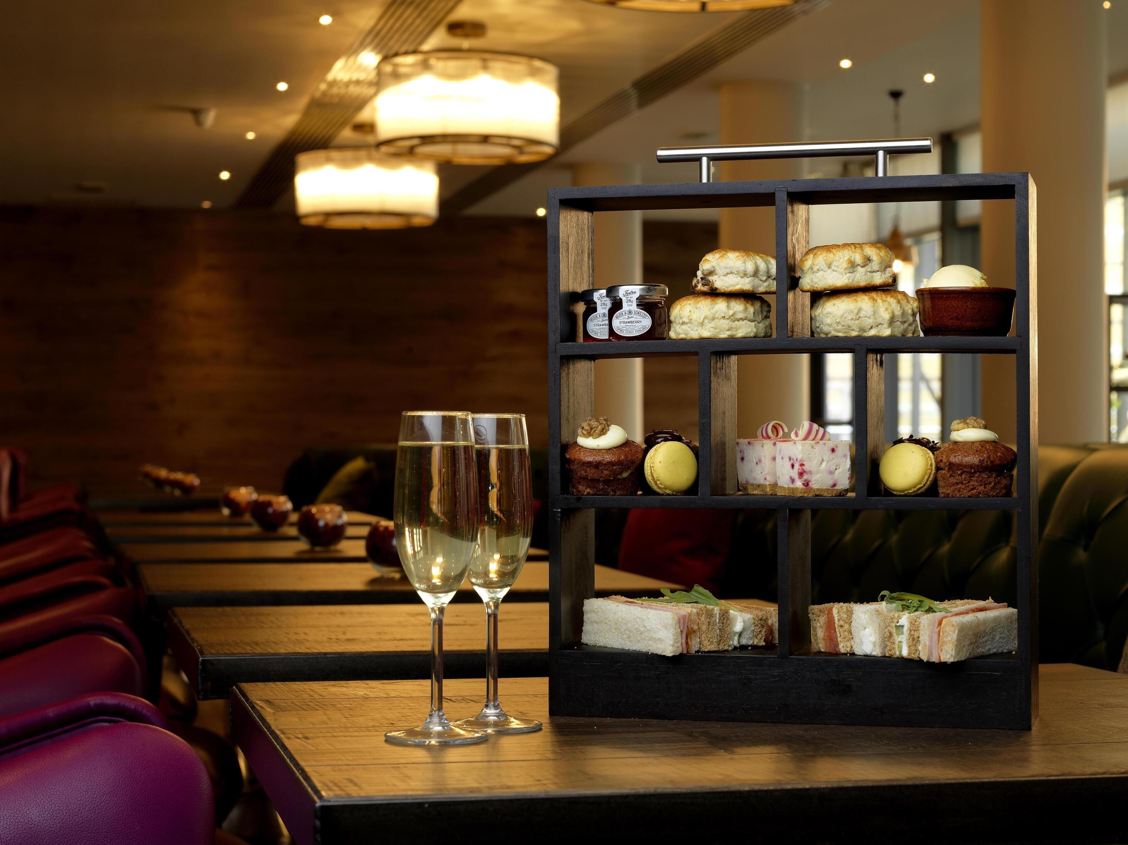 A dessert display with various pastries and a wine glass.