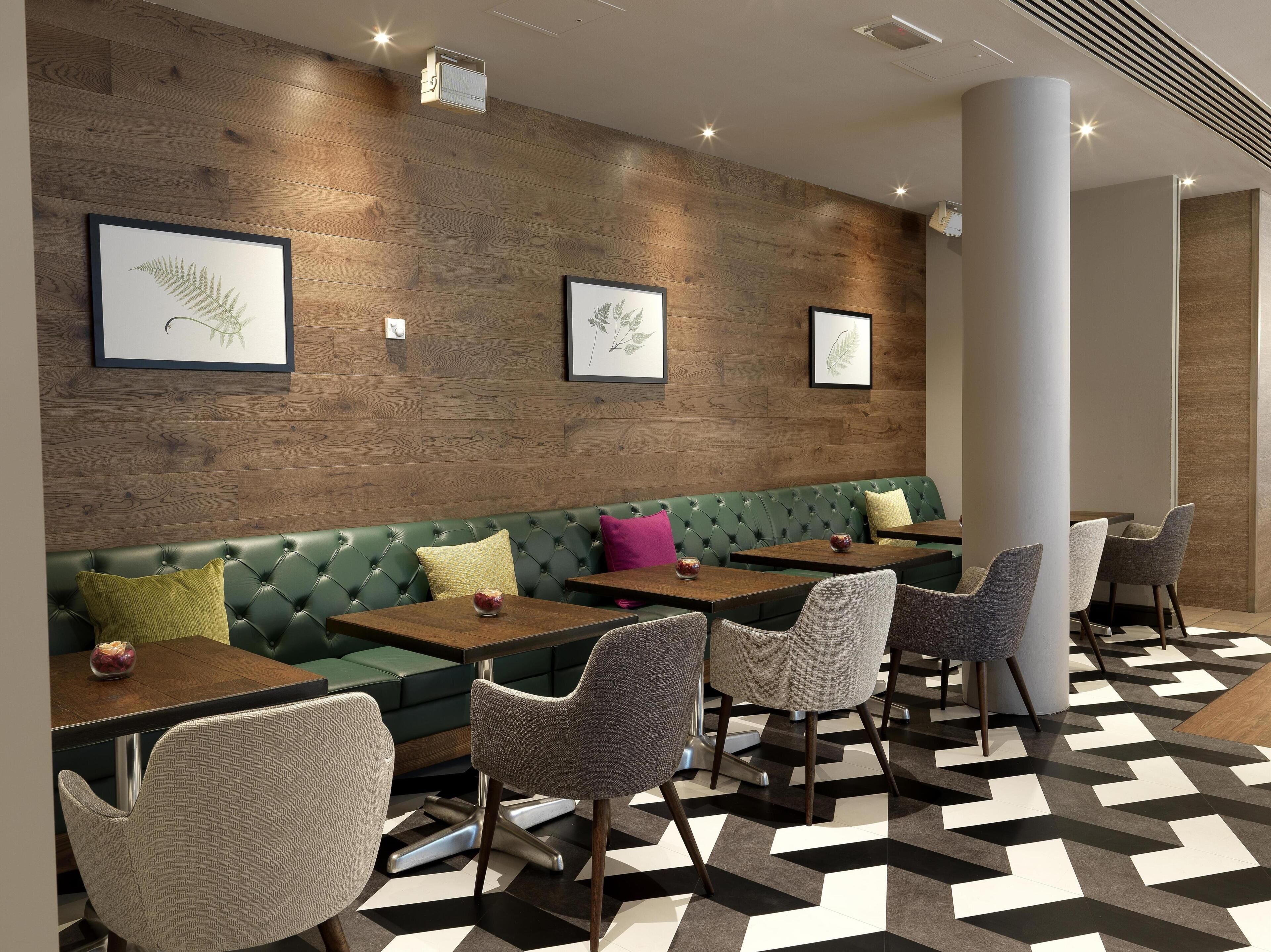 Ein modernes Interieur mit einer grünen gepolsterten Bank, mehreren Tischen und Stühlen.