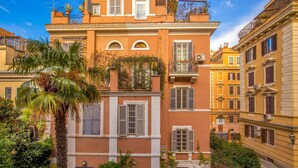 A multi-story building with balconies, a palm tree, and surrounding greenery. - Hotel Villa Glori (Rome)