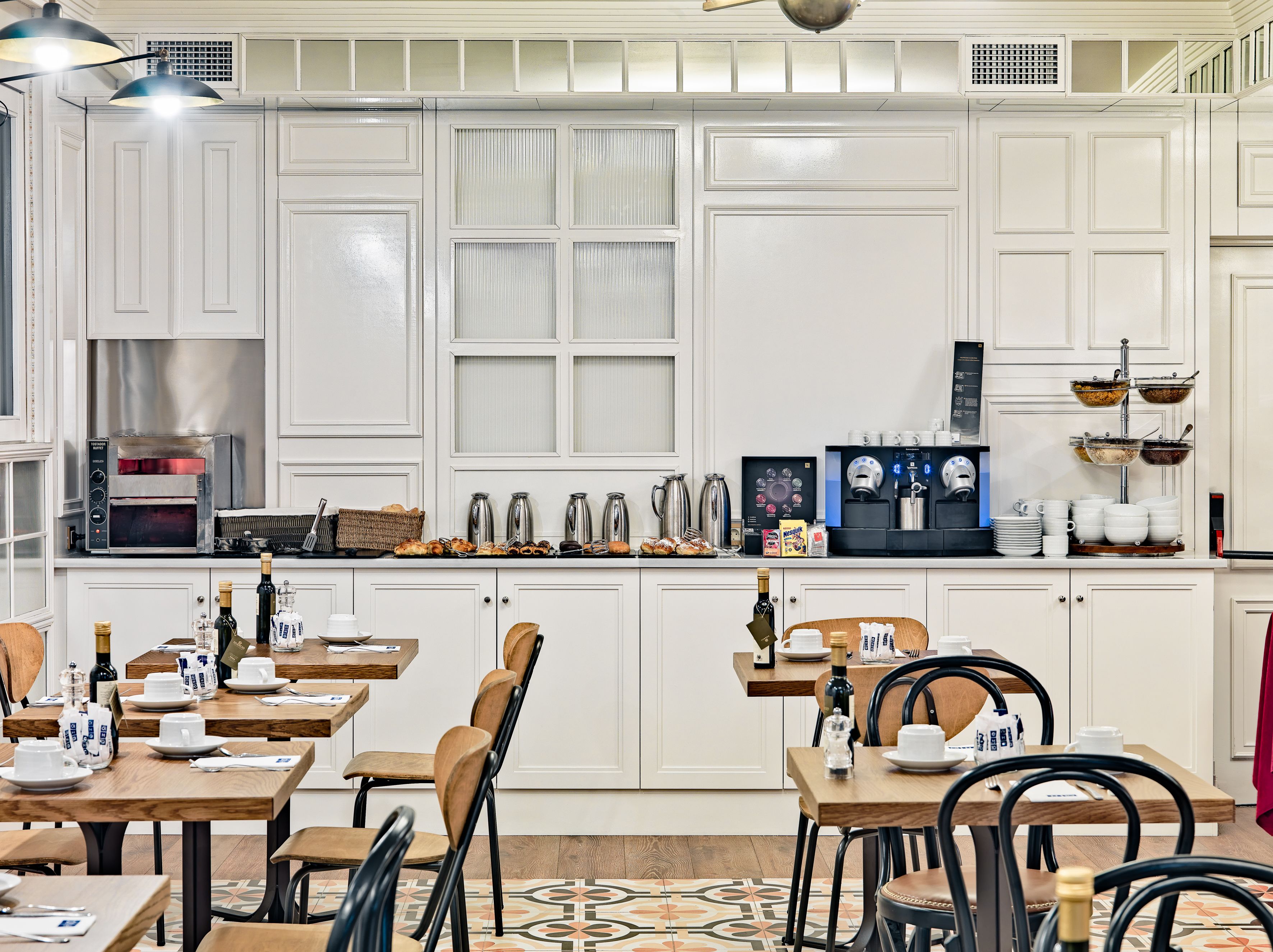 Una cocina moderna con armarios blancos, horno empotrado y espacio para café.