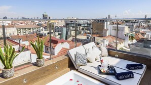A rooftop terrace with a hot tub, potted plants, and a seating area with a view of the city. - H10 Villa de la Reina Boutique Hotel (Madrid)