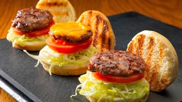 Een sandwich met een gegrilde burger, kaas, sla en tomaat op een geroosterde bol.