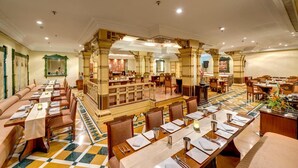 A spacious restaurant with high ceilings, ornate columns, and a central bar area. - The HHI Kolkata (Kolkata)