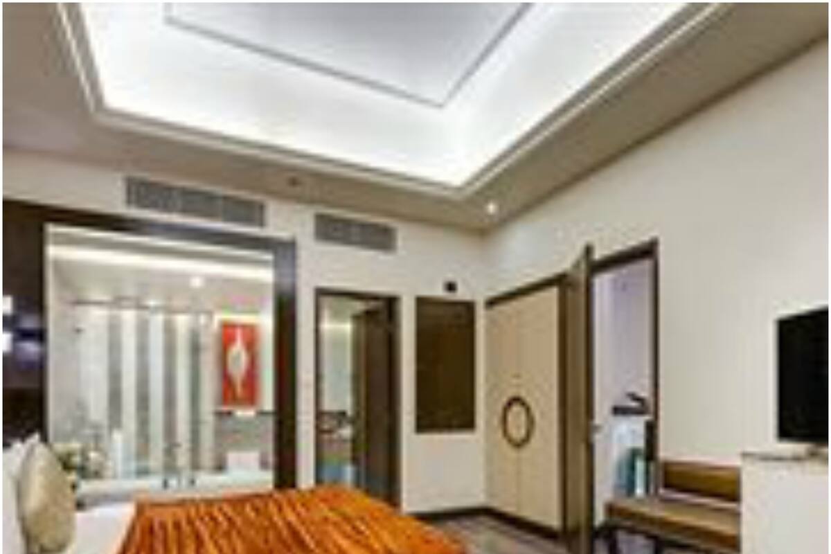 A hotel room with a large bed, a desk, a chair, a round table, and a television.
