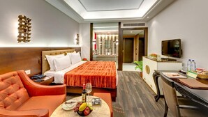 A modern hotel room with a large bed, a sofa, a desk with a computer, and a TV. - The HHI Kolkata (Kolkata)