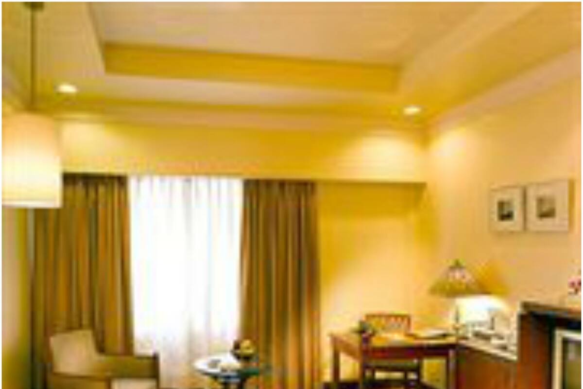 A hotel room with a bed, a desk, a chair, a television, and a window with curtains.