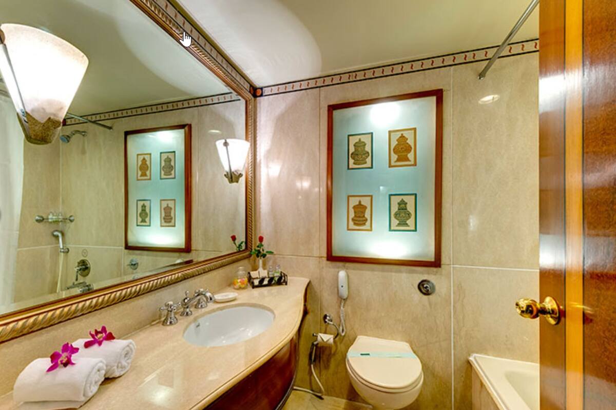 A bathroom with a large mirror, a sink, a toilet, and a bathtub.