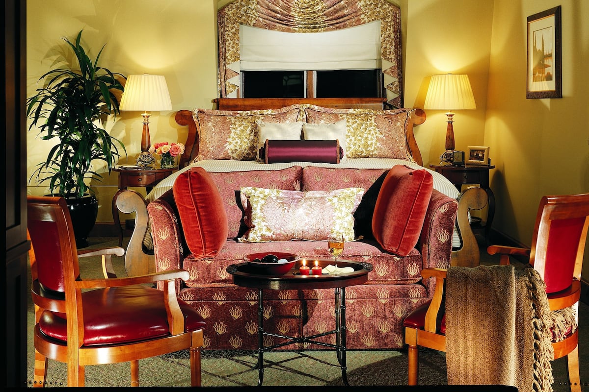 A hotel room with a large bed, a sitting area with a table, and two chairs.