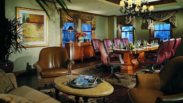 A spacious living room with leather chairs, a wooden dining table, and a chandelier.