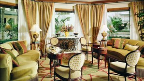 A well-appointed living room with a sofa set, armchairs, a coffee table, and a decorative lamp. - The Rose Hotel (Pleasanton)