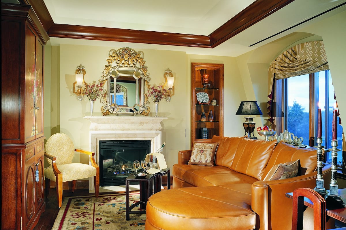 A living room with a fireplace, leather sofa, wooden cabinet, and a bookshelf.