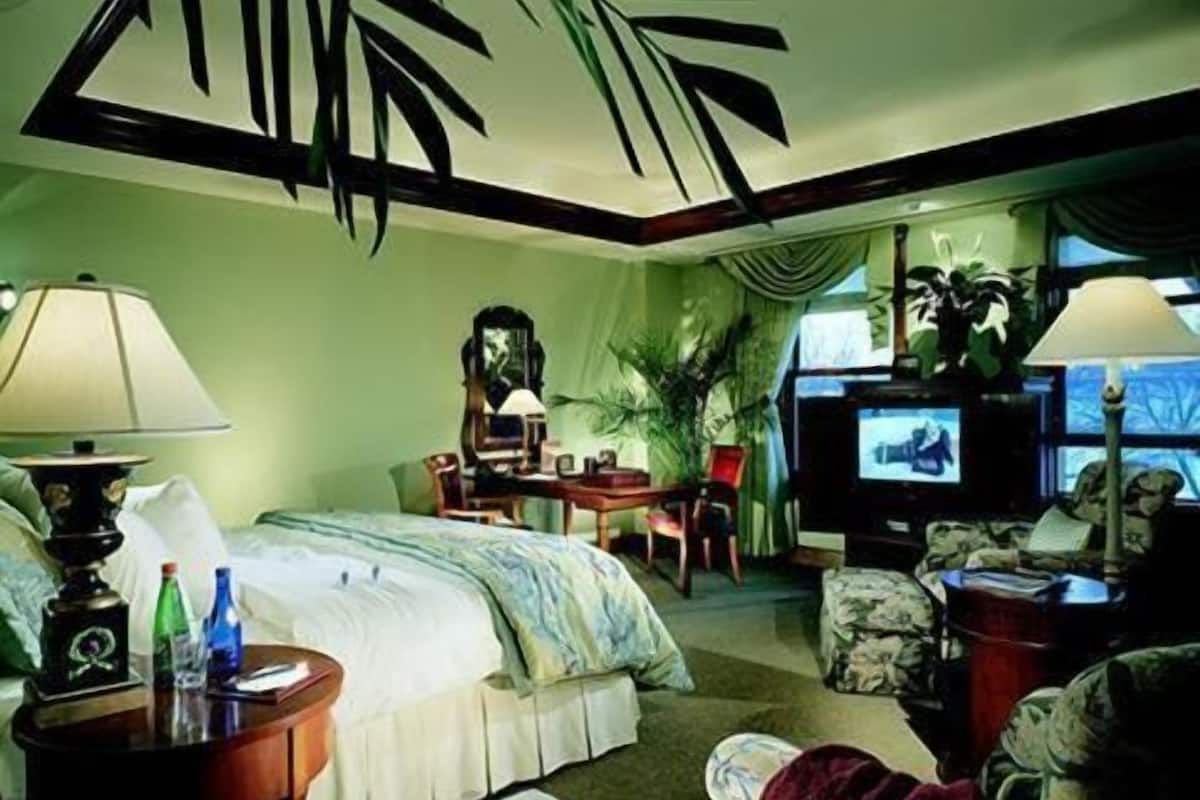 A hotel room with a bed, a desk, a television, and a chair.