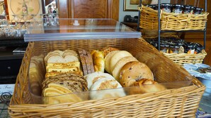 A display case with various types of bread and pastries. - The Rose Hotel (Pleasanton)