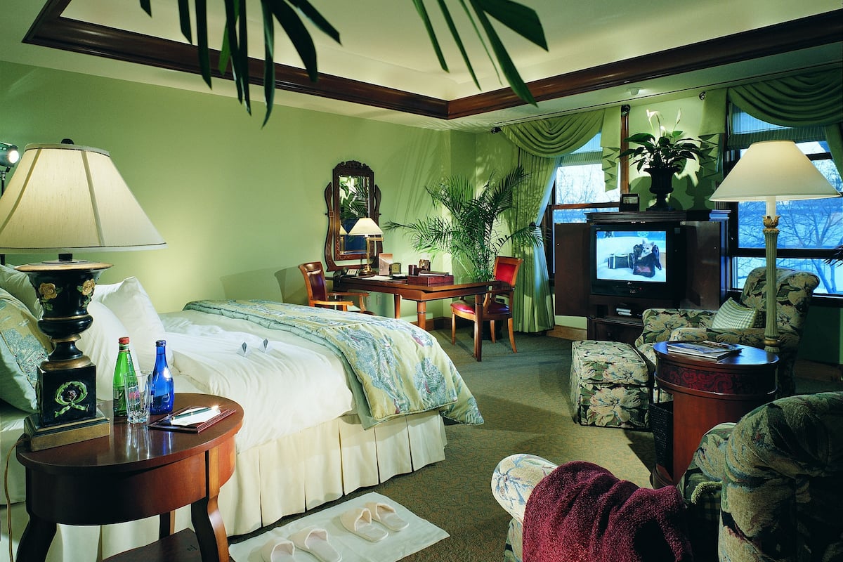 A hotel room with a bed, a desk, a television, and a chair.