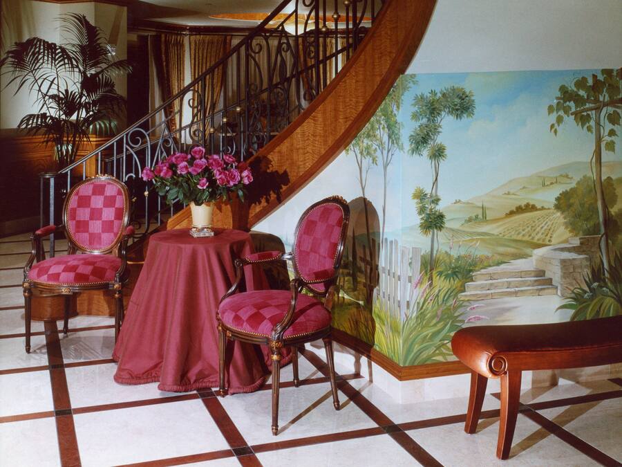 A staircase with a railing, a table with a vase of flowers, and two chairs with a checkered pattern.