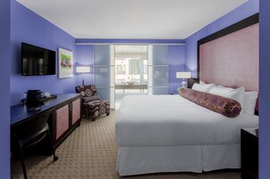 Habitación de hotel con una cama grande, un escritorio con silla, televisión y ventana con vista al exterior.