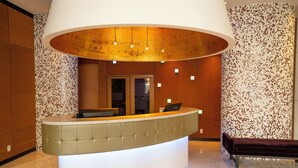 A reception area with a curved counter, a bench, and a patterned wall. - OPUS Hotel Vancouver (Vancouver)