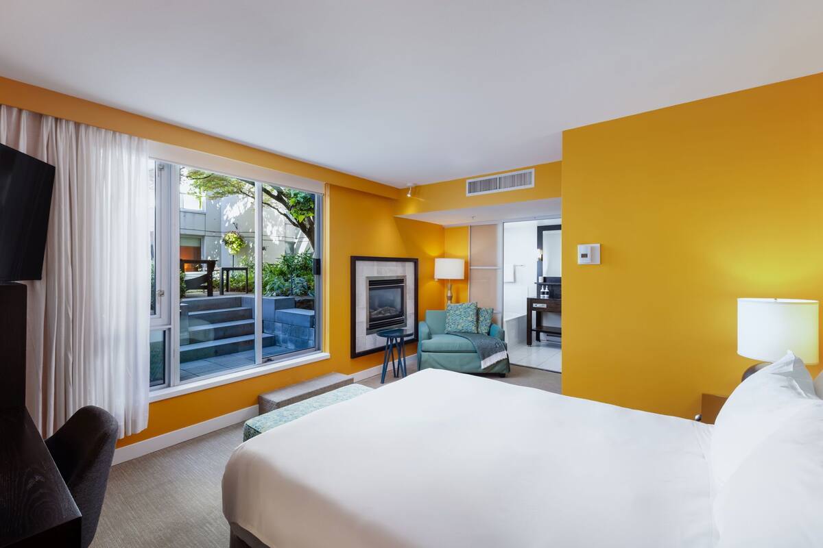 Habitación de hotel con una cama grande, televisión, sofá, escritorio y vistas al exterior.