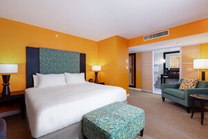 A hotel room with a large bed, two bedside tables with lamps, a green sofa, and a small table.