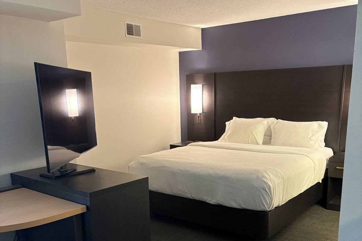 Een hotelkamer met een bed, een bureau, een televisie en een nachtkastje.