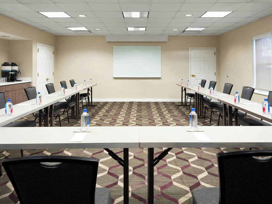 A conference room with a long table, chairs, a projector screen, and a coffee machine.
