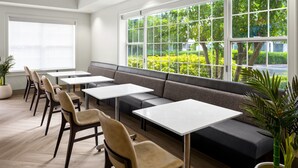 Un espace repas moderne avec un long banc, plusieurs tables et des chaises.
