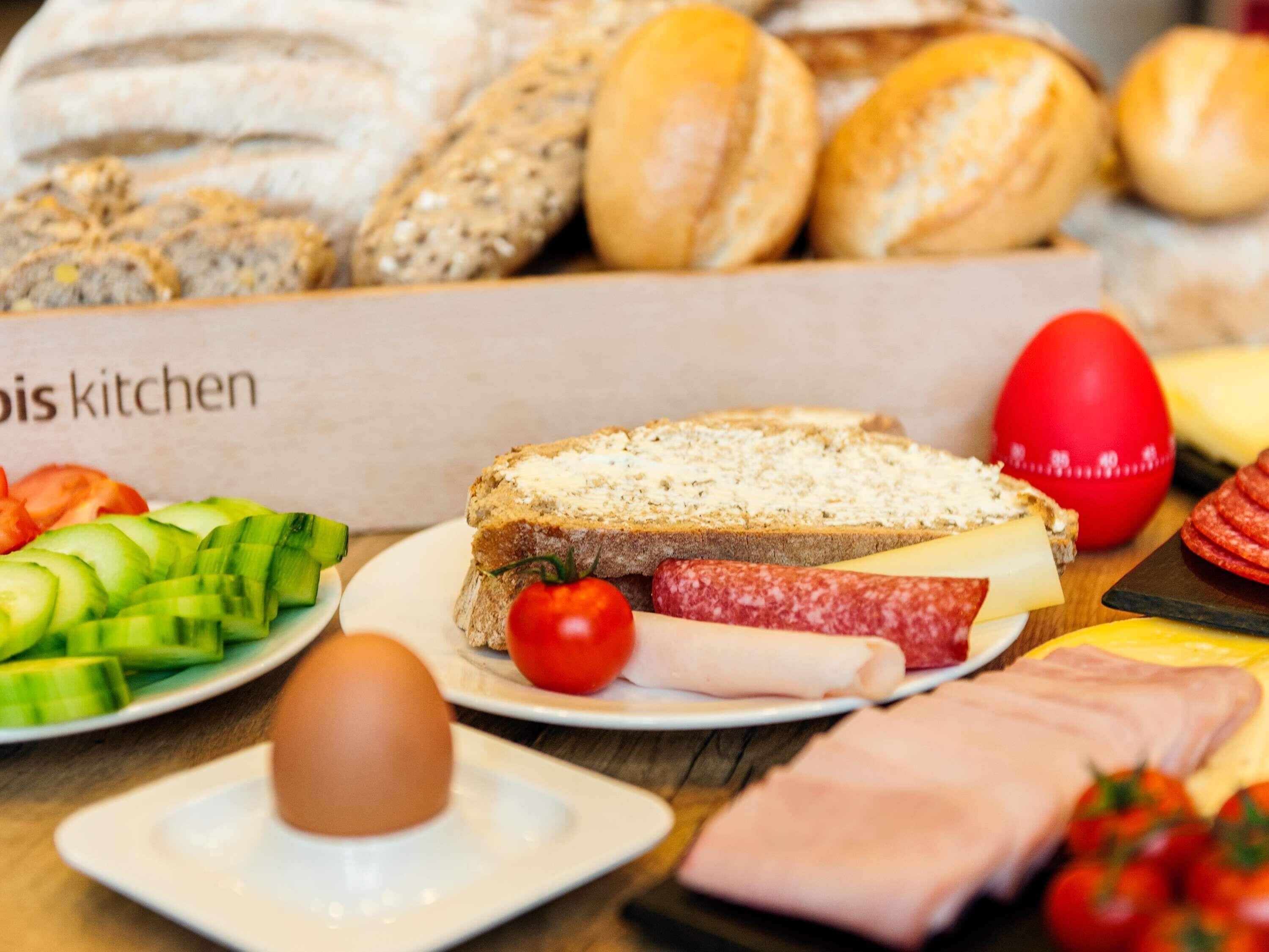 A table with various food items including bread, cheese, ham, and vegetables.