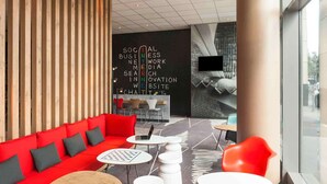 Un área de descanso moderna con un sofá rojo, mesas blancas y una pizarra con palabras relacionadas con negocios.