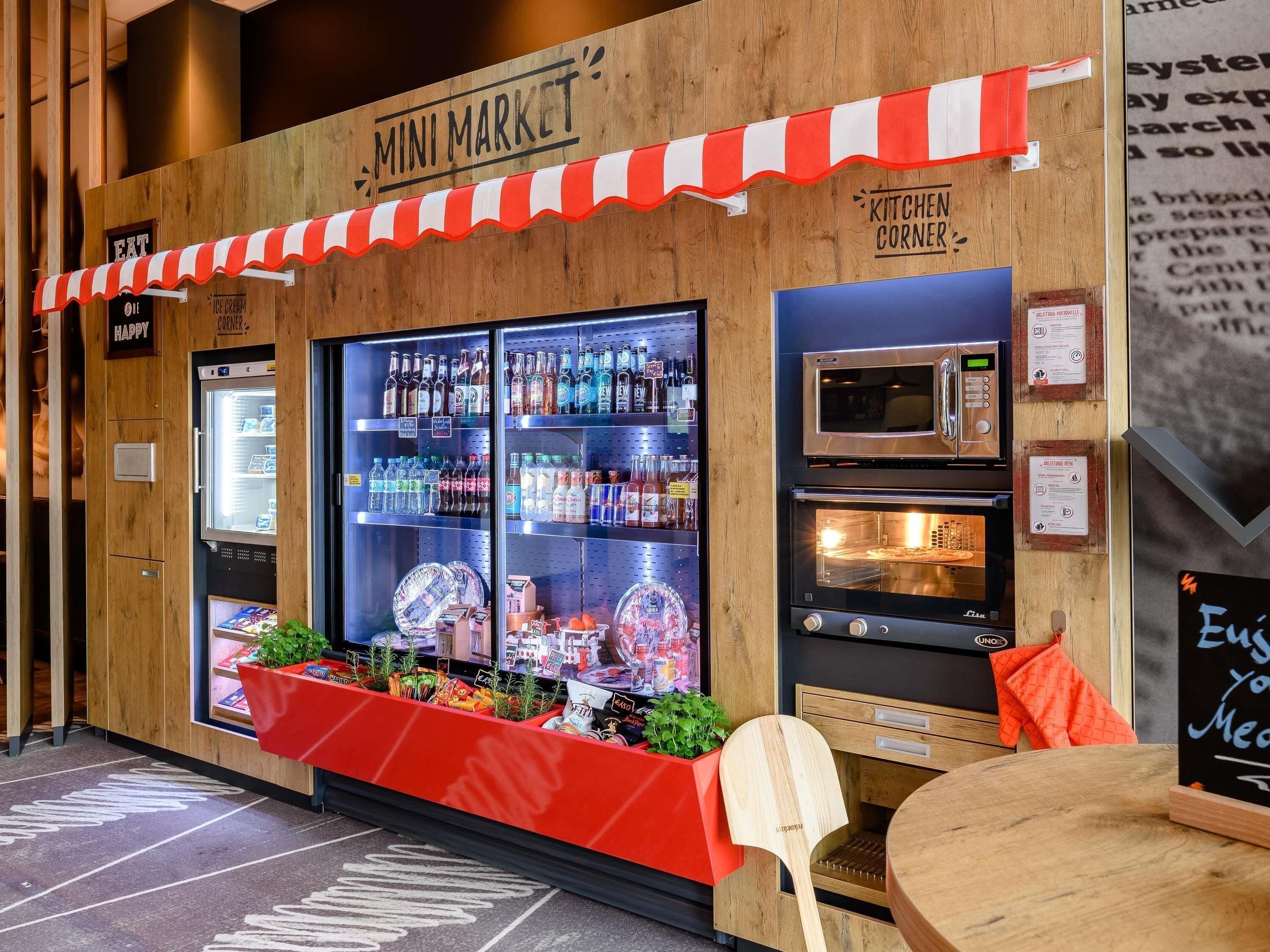 A mini market with a refrigerated display, a microwave, and a seating area.