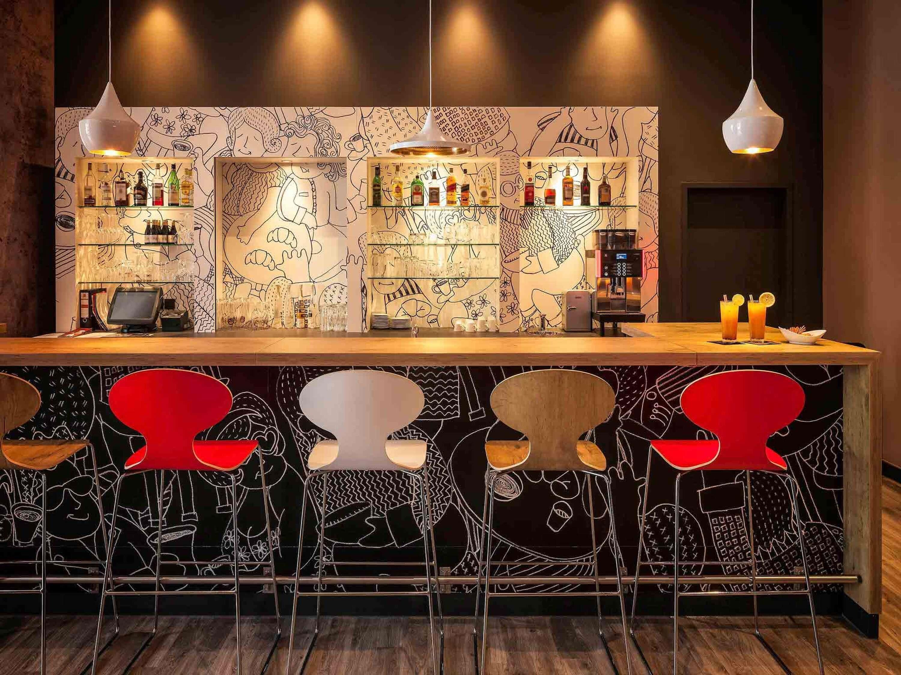 A bar area with a counter, bar stools, and a wall with line drawings.