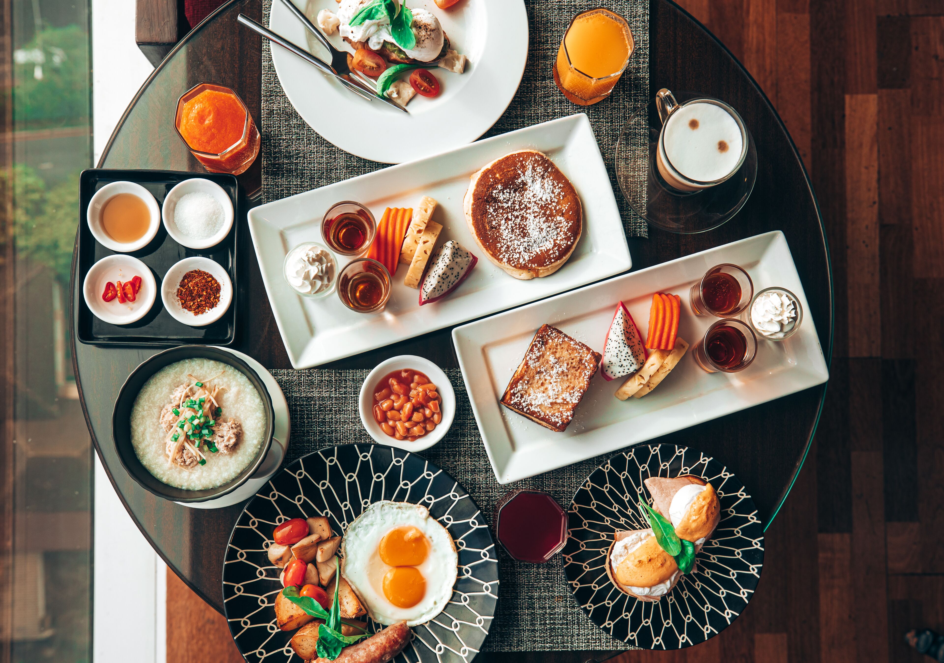 Un bufé de desayuno con diversos platos, como panqueques, huevos y tostadas, dispuesto en una mesa redonda.
