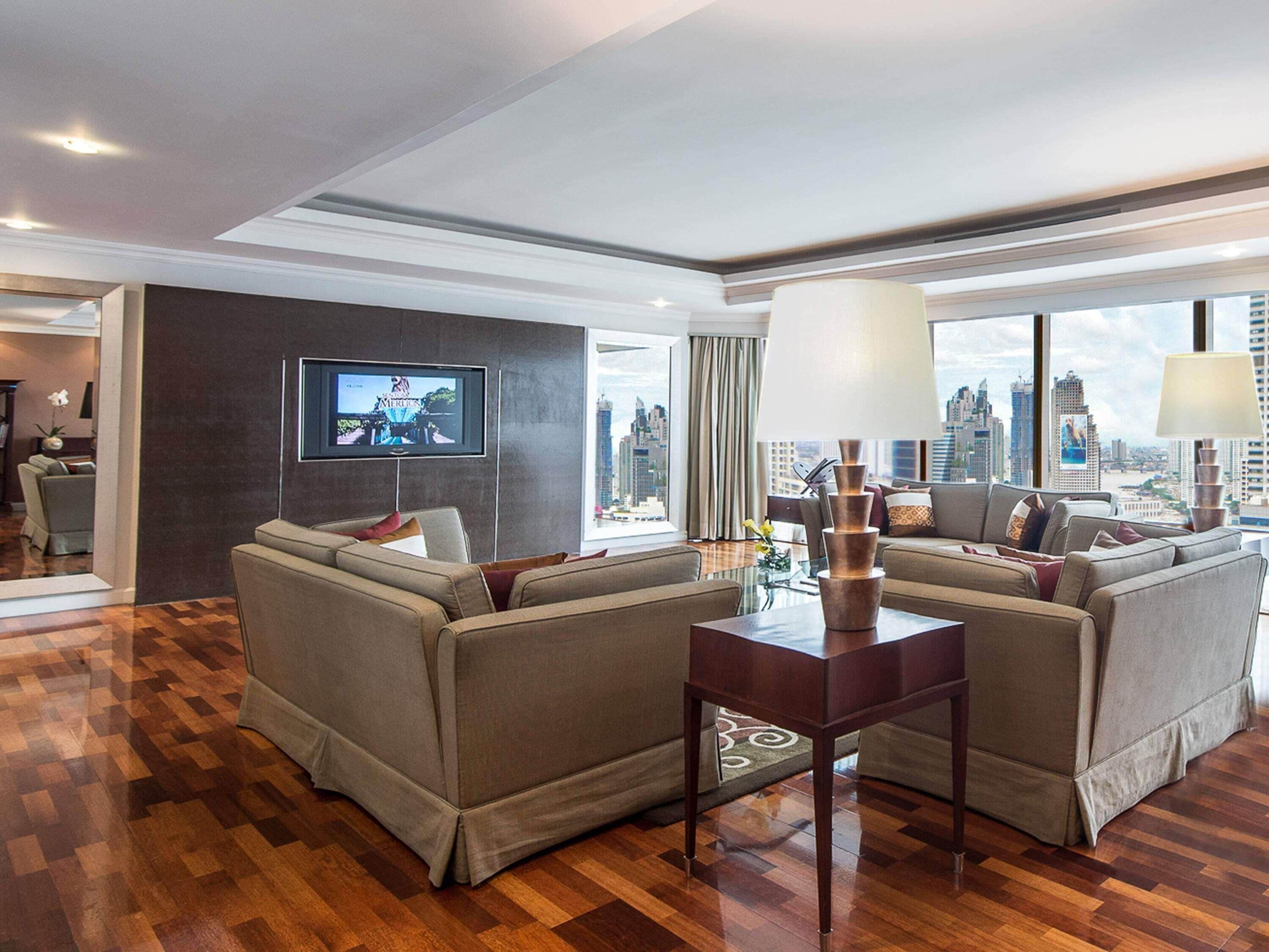 Une chambre d’hôtel moderne dotée d’un grand téléviseur à écran plat, de deux canapés, d’une table basse et offrant une vue sur la ville.